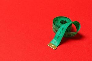 Perspective view of balled measuring tape on red background. Close up of slimming concept photo