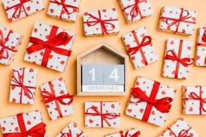 Top view of white gift boxes with hearts and wooden calendar on colorful background. The fourteenth of February. Valentine's Day concept photo