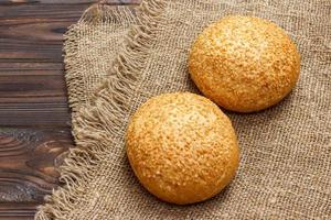 Fresh homemade bread rolls with sesam seeds on wooden table photo