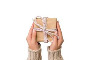 las manos de la mujer dan San Valentín envuelto u otro regalo hecho a mano en papel con cinta rosa. caja presente, decoración de regalo aislado en blanco foto
