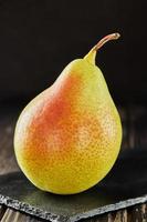 Fresh pear on black stone on wooden background photo