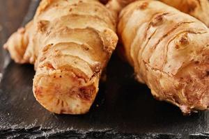 Fresh ginger on black stone on wooden background photo