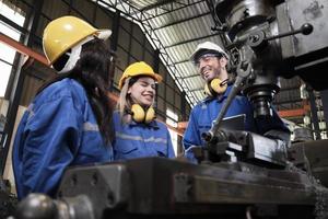 equipo de trabajadores industriales con uniformes de protección y seguridad, gerente masculino y colegas femeninas felices de trabajar con máquinas metalúrgicas en la fábrica de fabricación. ingeniero de producción mecánica profesional. foto