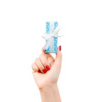 las manos de las mujeres dan Navidad envuelta u otro regalo hecho a mano en papel azul con cinta blanca. aislado sobre fondo blanco, vista superior. concepto de caja de regalo de acción de gracias foto