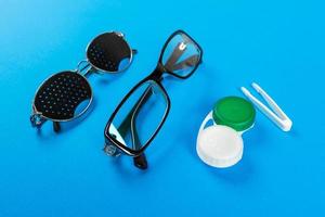 gafas estenopeicas, lentes con recipiente y gafas para la vista. concepto médico. un conjunto de accesorios para la vista. vista superior foto