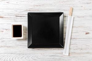 Empty black square slate plate with chopsticks for sushi on wooden background. Top view with copy space photo