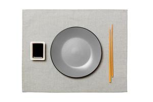 Empty round gray plate with chopsticks for sushi and soy sauce on grey napkin background. Top view with copy space for you design photo