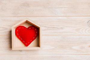 vista superior del corazón textil rojo en una casa sobre fondo de madera. concepto de hogar dulce hogar. día de San Valentín foto