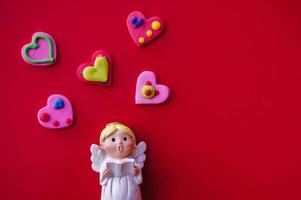 Cupid doll and heart-shaped on red background photo