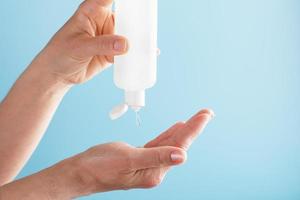 A bottle of Disinfectant gel in your hands on a blue background. Antiseptic treatment of hands from bacteria Sanitizer. photo