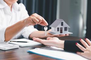 Business person hands holding home model, small building red house. Real estate agents offer contracts to purchase or rent residential. Mortgage property insurance moving home and real estate concept photo