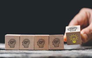 Concept creative idea and innovation. Hand choose wooden cube block with head human symbol and light bulb icon. knowledge and education concept. learning with smart technology. photo