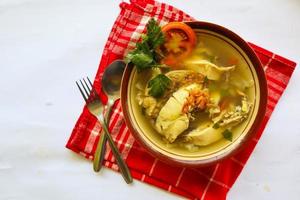 Chicken soup served with vegetables, tomatoes, celery in a bowl, spoon and fork. with black background photo