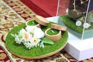 par de anillos de boda con decoración de rosas en una alfombra de terciopelo foto