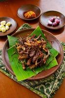 fried grasshopper or belalang goreng is traditional food from southeast asia, served with sambal, onion, garlic, chili on wood background photo