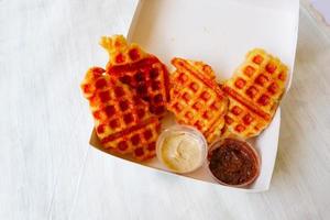 gofre croissant o croffle con salsa de chocolate servido en caja y fondo blanco foto