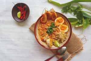 laksa, laksa curry made from vermicelli, noodles, bean sprouts, egg, tofu lime, and shrimp with a spicy soup sauce that is rich in spices. laksa served on bowl, isolated on white background. photo