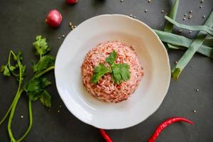 Red steamed rice or nasi merah served in plate isolated on black background photo