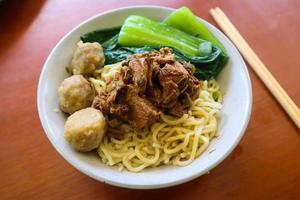 mie ayam or noodles chicken is traditional food from indonesia, asia made from noodle, chicken, chicken broth, spinach, sometimes with meatball. photo