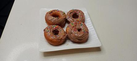 assorted donuts with chocolate frosted, pink glazed and sprinkles donuts. Donuts in hand or tray photo