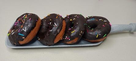 assorted donuts with chocolate frosted, pink glazed and sprinkles donuts. Donuts in hand or tray photo