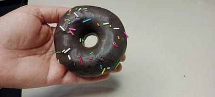 assorted donuts with chocolate frosted, pink glazed and sprinkles donuts. Donuts in hand or tray photo