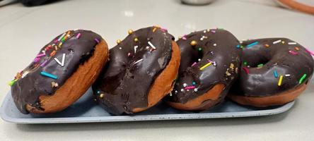 assorted donuts with chocolate frosted, pink glazed and sprinkles donuts. Donuts in hand or tray photo