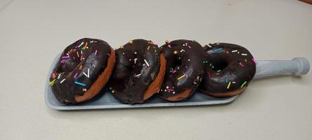 assorted donuts with chocolate frosted, pink glazed and sprinkles donuts. Donuts in hand or tray photo