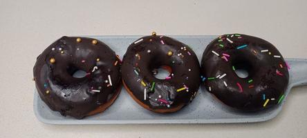 assorted donuts with chocolate frosted, pink glazed and sprinkles donuts. Donuts in hand or tray photo