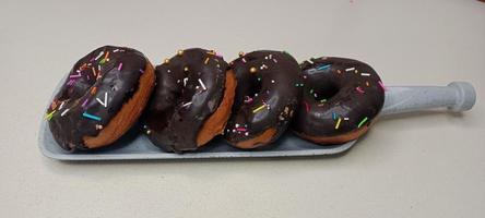 assorted donuts with chocolate frosted, pink glazed and sprinkles donuts. Donuts in hand or tray photo