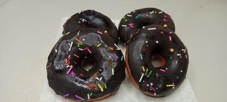 assorted donuts with chocolate frosted, pink glazed and sprinkles donuts. Donuts in hand or tray photo