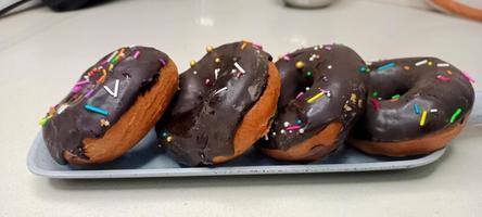 assorted donuts with chocolate frosted, pink glazed and sprinkles donuts. Donuts in hand or tray photo