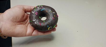 assorted donuts with chocolate frosted, pink glazed and sprinkles donuts. Donuts in hand or tray photo