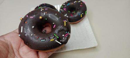 assorted donuts with chocolate frosted, pink glazed and sprinkles donuts. Donuts in hand or tray photo