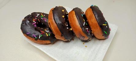 assorted donuts with chocolate frosted, pink glazed and sprinkles donuts. Donuts in hand or tray photo