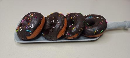 assorted donuts with chocolate frosted, pink glazed and sprinkles donuts. Donuts in hand or tray photo