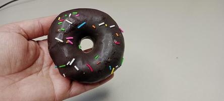 assorted donuts with chocolate frosted, pink glazed and sprinkles donuts. Donuts in hand or tray photo