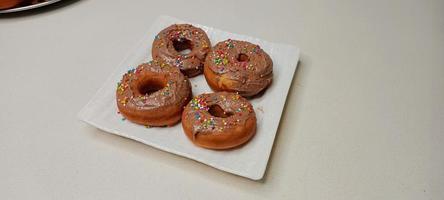 assorted donuts with chocolate frosted, pink glazed and sprinkles donuts. Donuts in hand or tray photo