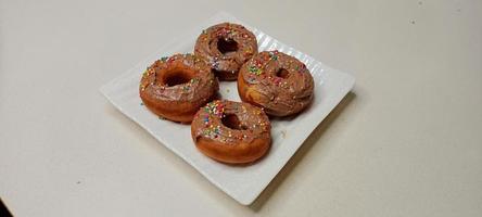 assorted donuts with chocolate frosted, pink glazed and sprinkles donuts. Donuts in hand or tray photo