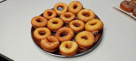 assorted donuts with chocolate frosted, pink glazed and sprinkles donuts. Donuts in hand or tray photo