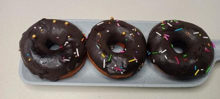 assorted donuts with chocolate frosted, pink glazed and sprinkles donuts. Donuts in hand or tray photo