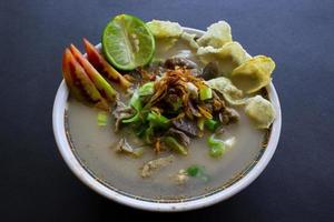 sop kaki kambing una comida tradicional de betawi, yakarta indonesia, hecha de cordero o cordero, despojos, especias. aislado sobre fondo negro. Esta comida es como estofado de cordero sobre fondo negro foto