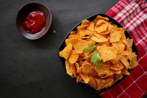 tortilla chip is corn chips or call nachos, served in bowl, on black background made from corn photo