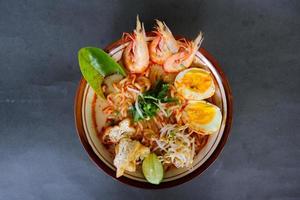 laksa, laksa curry made from vermicelli, noodles, bean sprouts, egg, tofu lime, and shrimp with a spicy soup sauce that is rich in spices. laksa served on bowl, isolated on white background. photo