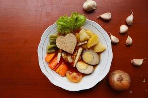 selat solo is traditional salad food from indonesia. made from hard-boiled eggs, boiled chickpeas, boiled carrots, hash browns and lettuce, steak or bistik. served on wood table photo