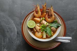 Tom yam soup originating from Thailand. Tom yum is made with shrimp, chili, lime, chicken, fish, or seafood and mushrooms. photo