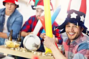 Happy male friends cheering and watching sports on tv photo