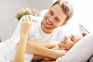 Happy couple with pregnancy test in bed photo