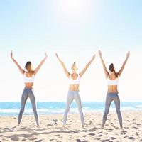 Group of women practising yoga on the beach photo