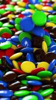 Round multicolored candies fall on the pile Vertical looped video